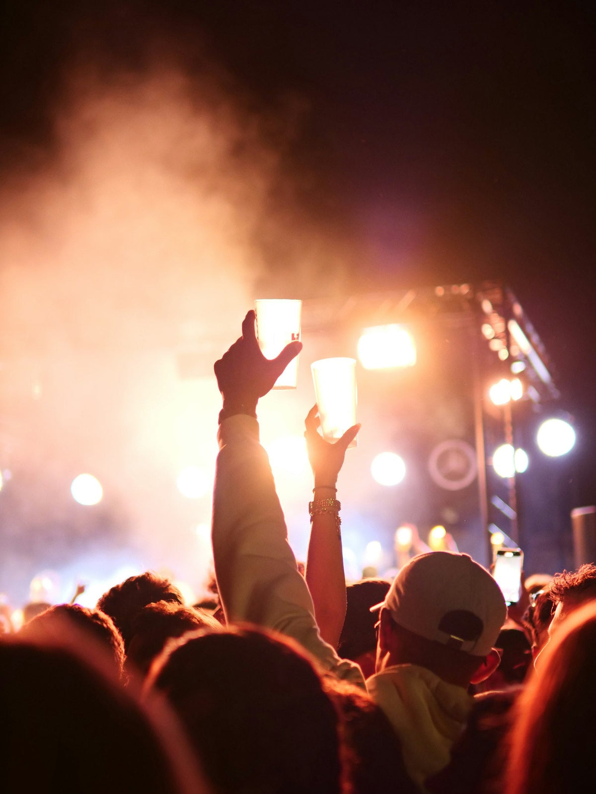 Concert crowd holding up phone lights under purple stage lights